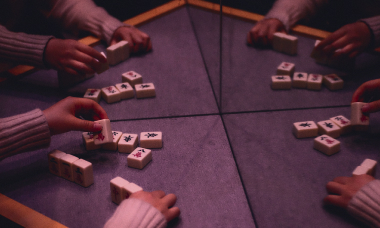 Руки четырех человек играющих в настольную игру